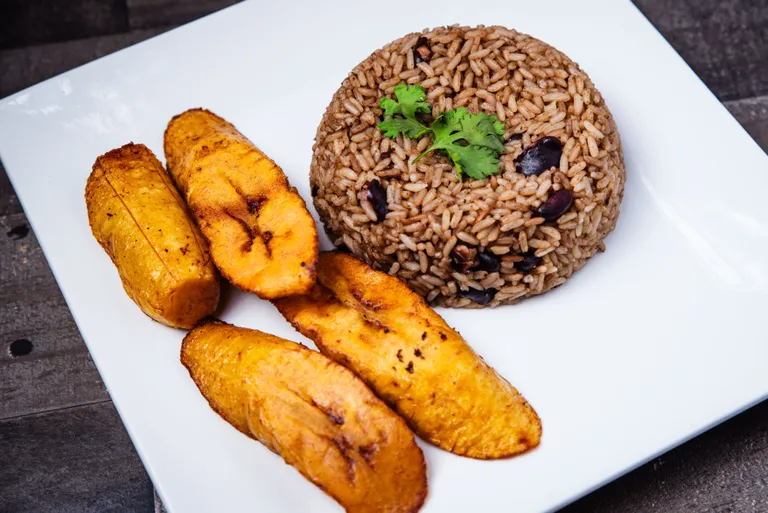 Coconut rice and peas with fried sweet plantain on a white plate