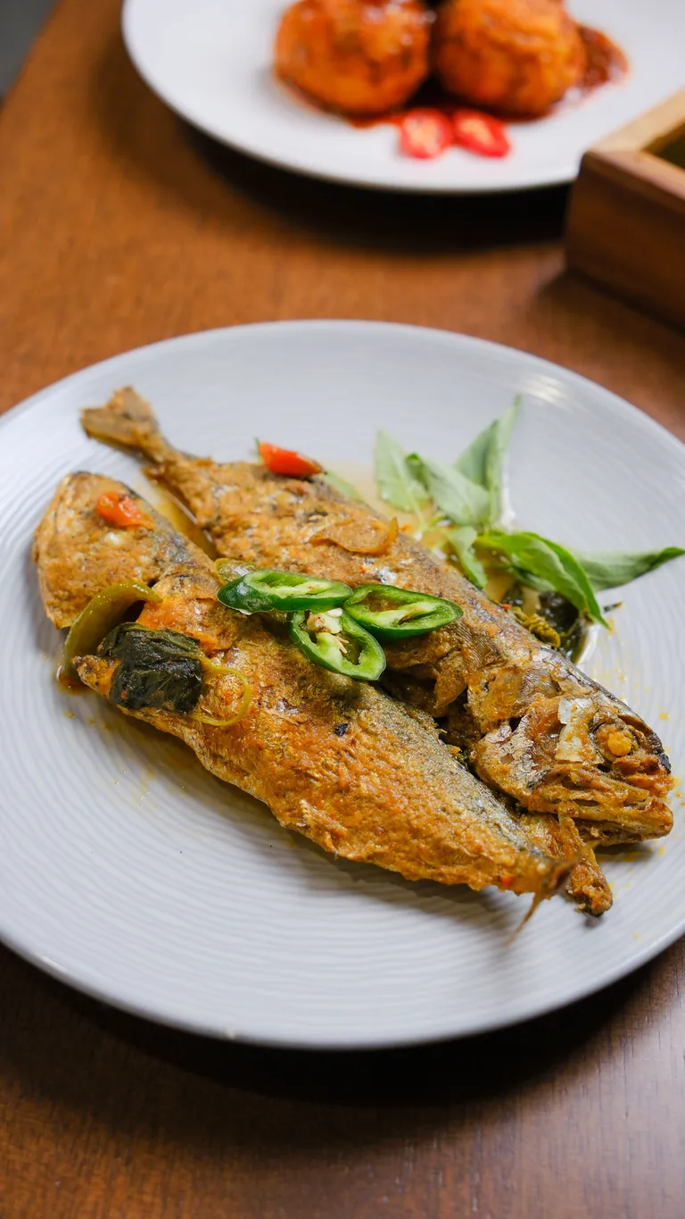 Whole fried fish topped with sliced chilies and fresh herbs